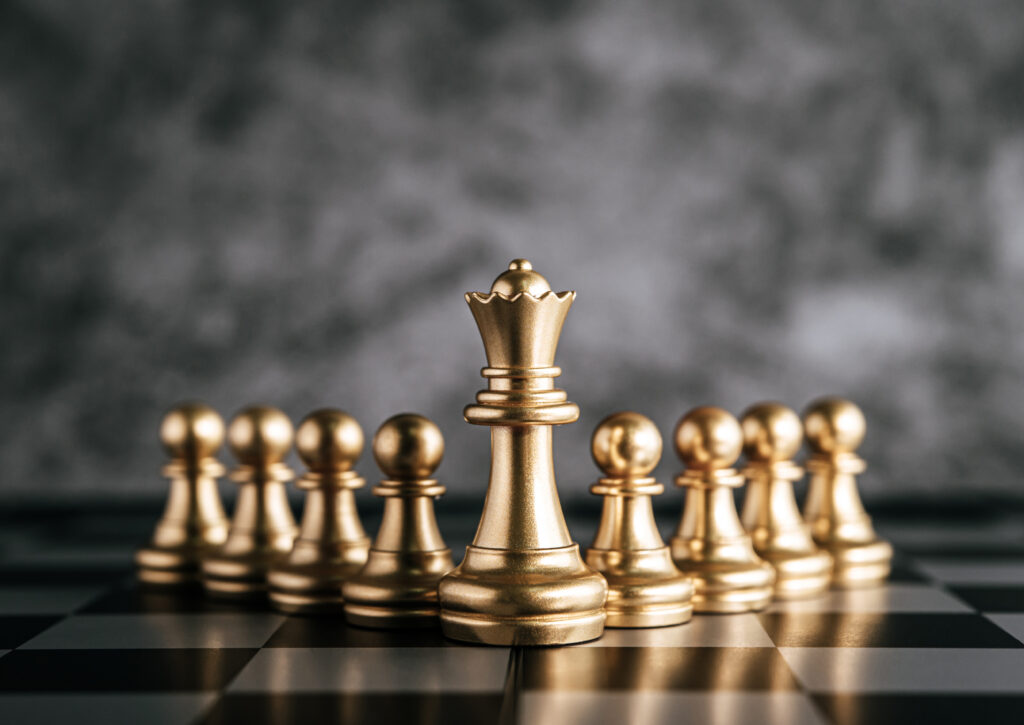 Golden chess pieces on a chess board with a dark grey background.